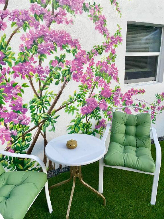two chairs and a table in front of a wall with purple flowers at Cozy Casarita Cottage in Miami