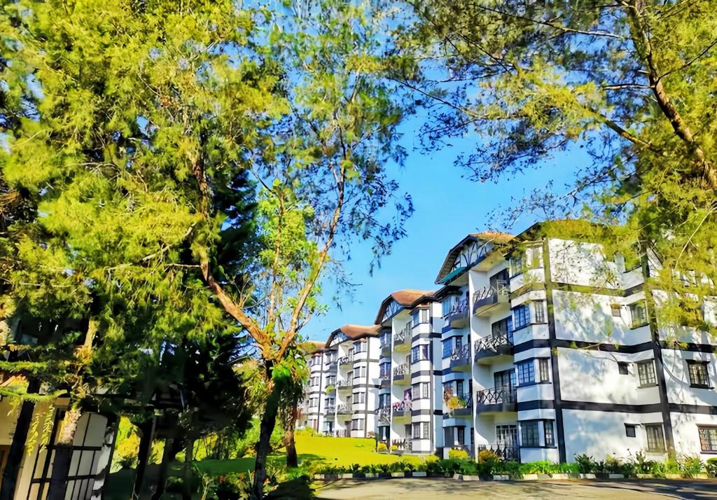 an apartment building with trees in the foreground at Greenhill Resort Cameron Highland in Tanah Rata