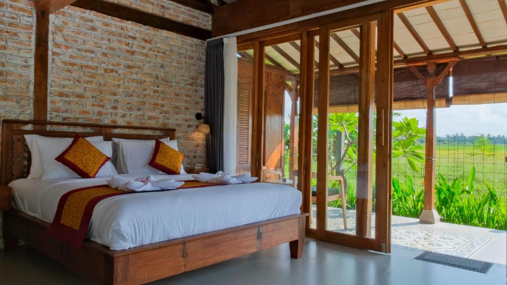 a bedroom with a bed and a large window at Rumah Tengah Sawah Bali in Ubud