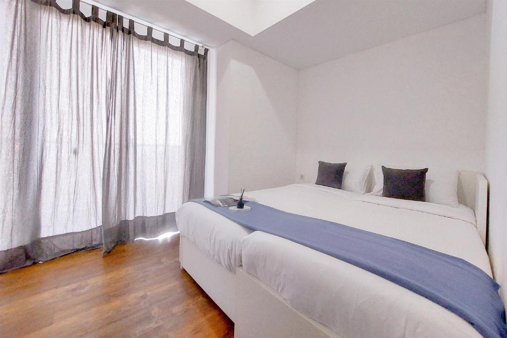 une chambre blanche avec une grande fenêtre et un lit dans l'établissement Cozy Living 2BR Apartment at Casa de Parco By Travelio, à Tangerang