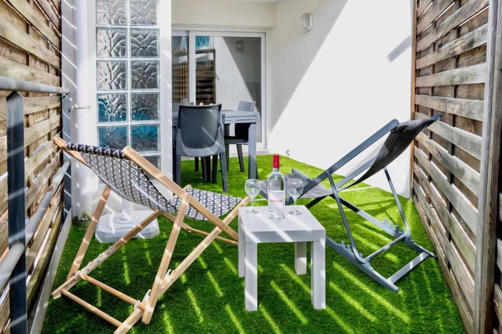 a patio with a table and chairs on grass at Residence du Centre Joli studio rénové avec coin nuit terrasse et parking privé in Capbreton