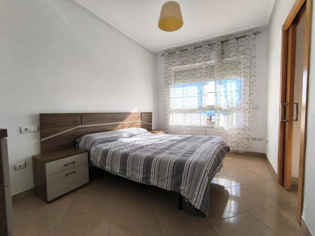 a bedroom with a large bed and a window at APARTAMENTO TURISTICO 2ºD CARLOS III - Cerca de la playa in Roquetas de Mar