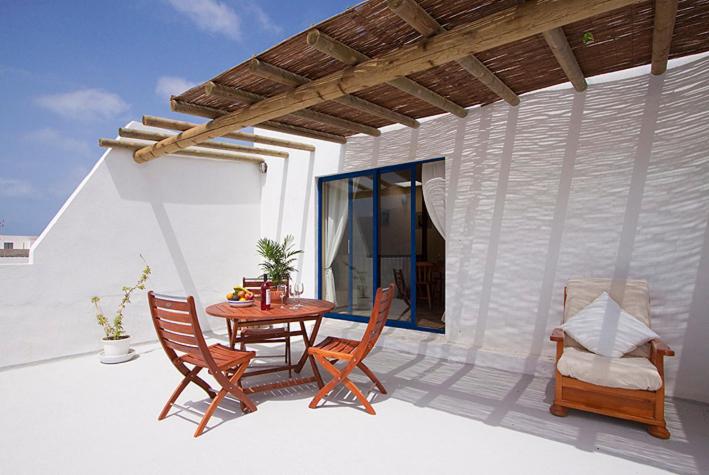 a patio with a wooden table and chairs on a house at Casa del Rio in Caleta de Sebo