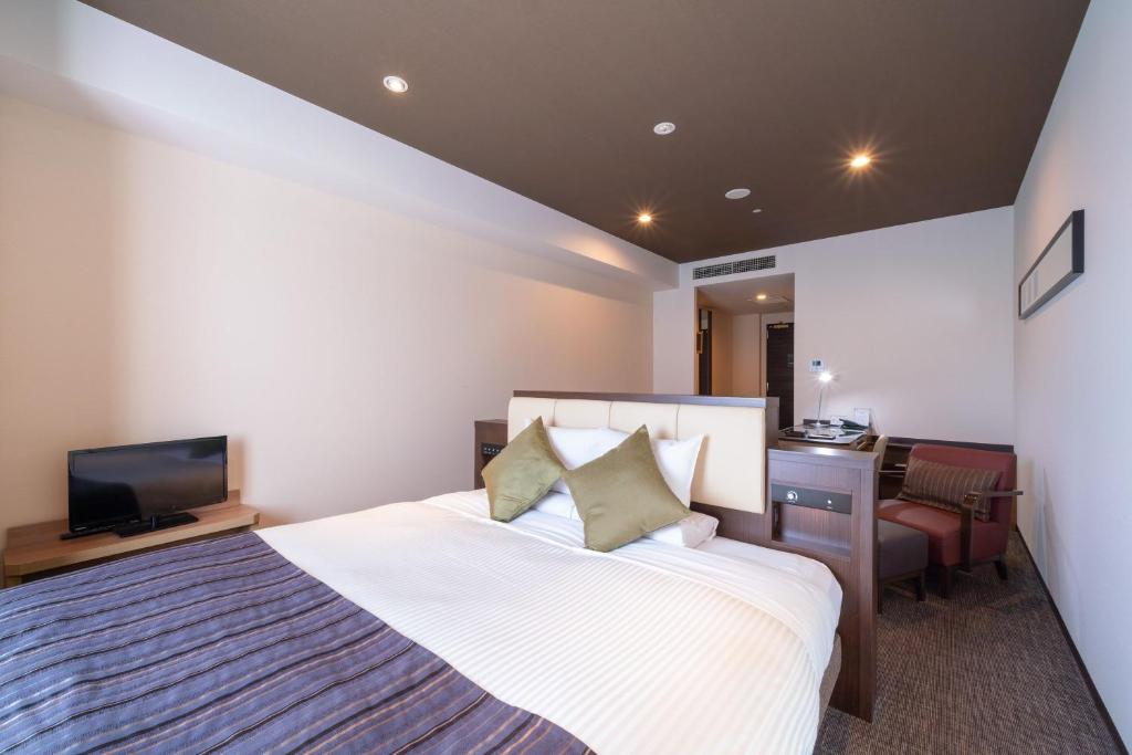 a bedroom with a bed and a desk and a television at HOTEL MYSTAYS PREMIER Kanazawa in Kanazawa