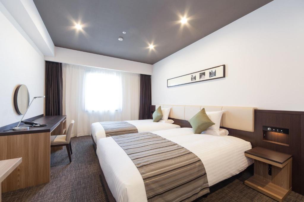 a hotel room with two beds and a desk at HOTEL MYSTAYS PREMIER Kanazawa in Kanazawa