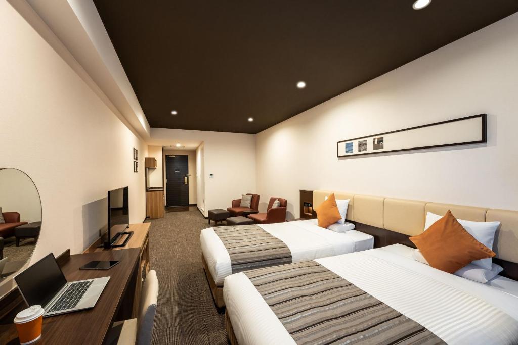 a hotel room with two beds and a desk at HOTEL MYSTAYS PREMIER Kanazawa in Kanazawa