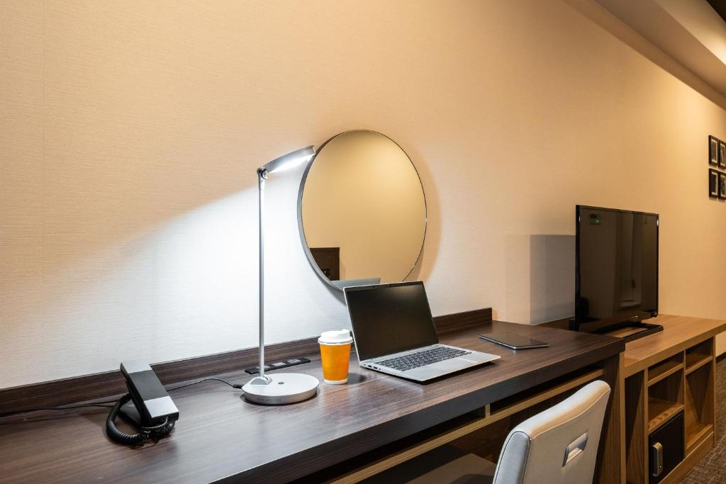 a room with a desk with a laptop and a mirror at HOTEL MYSTAYS PREMIER Kanazawa in Kanazawa