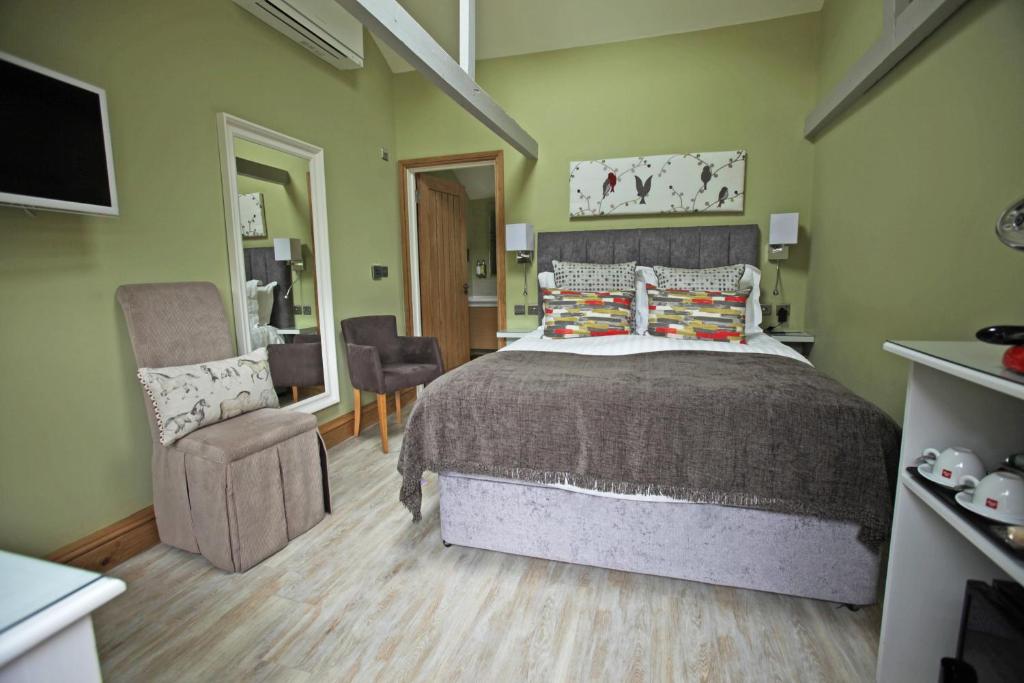 um quarto com uma cama grande e uma cadeira em The Black Horse at Ireland em Shefford