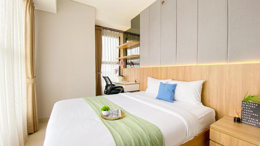 ein Schlafzimmer mit einem großen weißen Bett und einem Tablett darauf in der Unterkunft Homey and Good Place 2BR Transpark Bintaro Apartment By Travelio in Tangerang