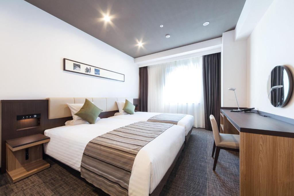 a hotel room with a large bed and a desk at HOTEL MYSTAYS PREMIER Kanazawa in Kanazawa