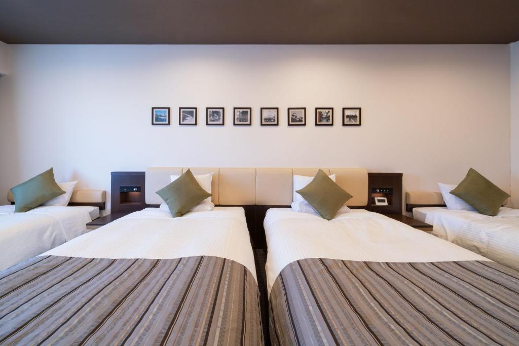 a room with three beds with pillows at HOTEL MYSTAYS PREMIER Kanazawa in Kanazawa