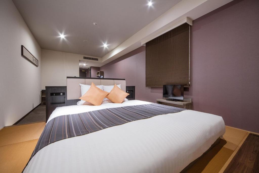 a bedroom with a large white bed with purple walls at HOTEL MYSTAYS PREMIER Kanazawa in Kanazawa