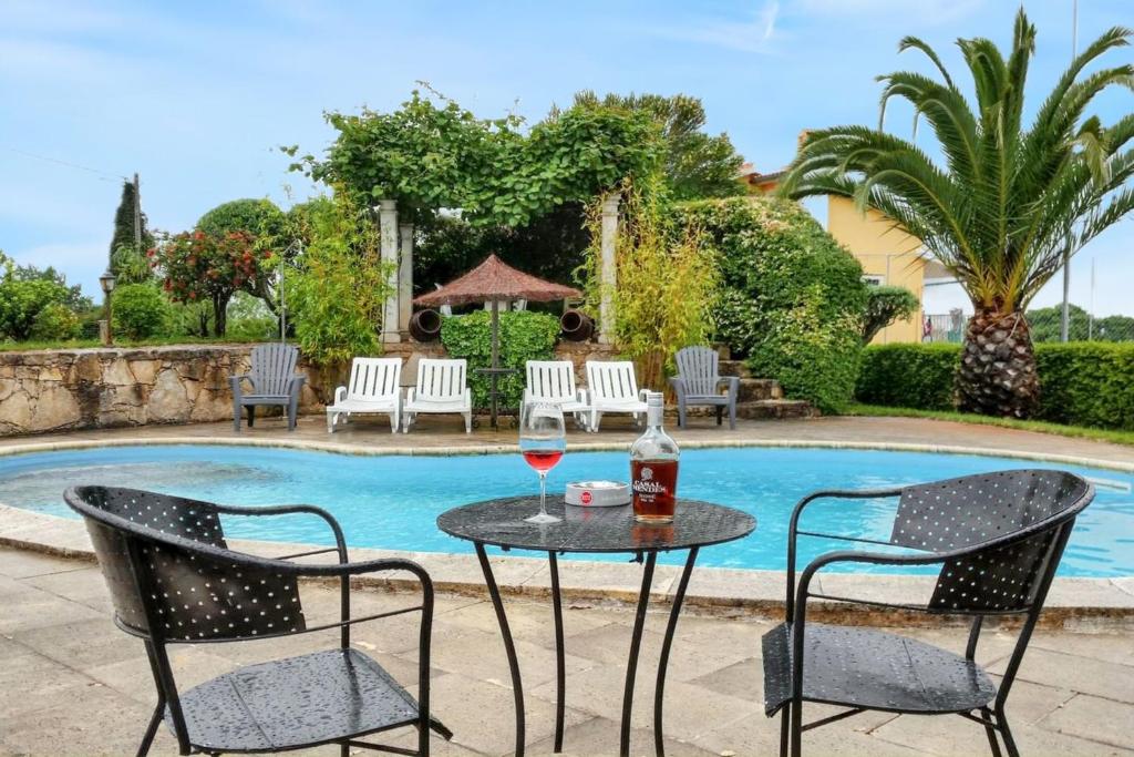 un tavolo con un bicchiere di vino e due sedie a bordo piscina di Charming Villa in Igreja Nova do Sobral with Private Pool a Sobral