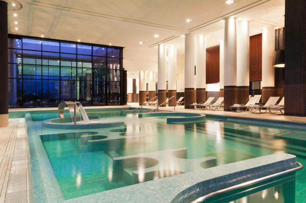 a swimming pool in a hotel with lounge chairs at Hôtel Barrière le Grand Hôtel Enghien-les-Bains in Enghien-les-Bains