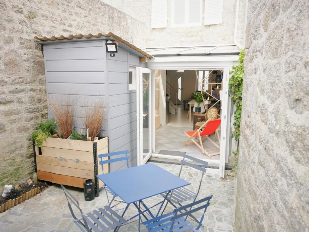 patio z niebieskimi krzesłami i garażem w obiekcie L'Héméra: Maison au coeur de Barfleur w mieście Barfleur