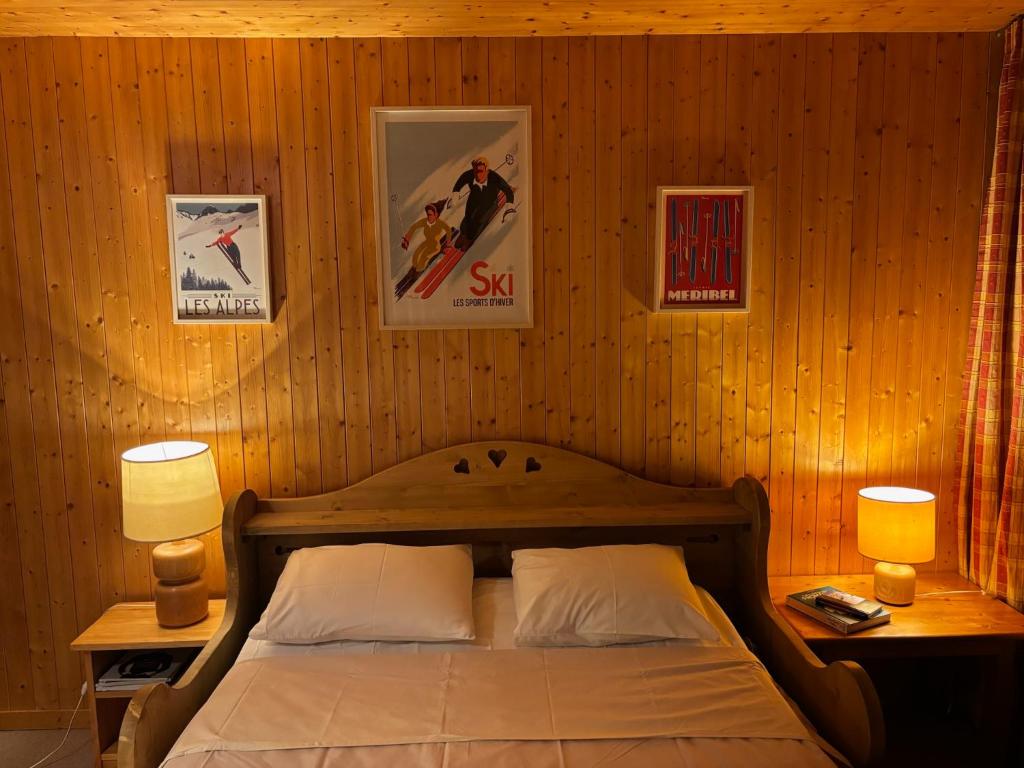 a bedroom with a bed with two lamps and pictures on the wall at Appartement 4 personnes - Magnifique vue montagne in Méribel