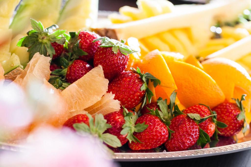 a plate of fruit with strawberries and oranges at HOTEL MYSTAYS PREMIER Kanazawa in Kanazawa