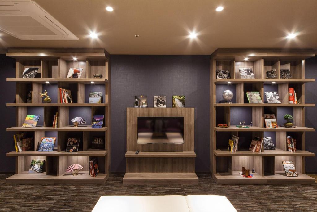 a room with a fireplace and shelves with books at HOTEL MYSTAYS PREMIER Kanazawa in Kanazawa
