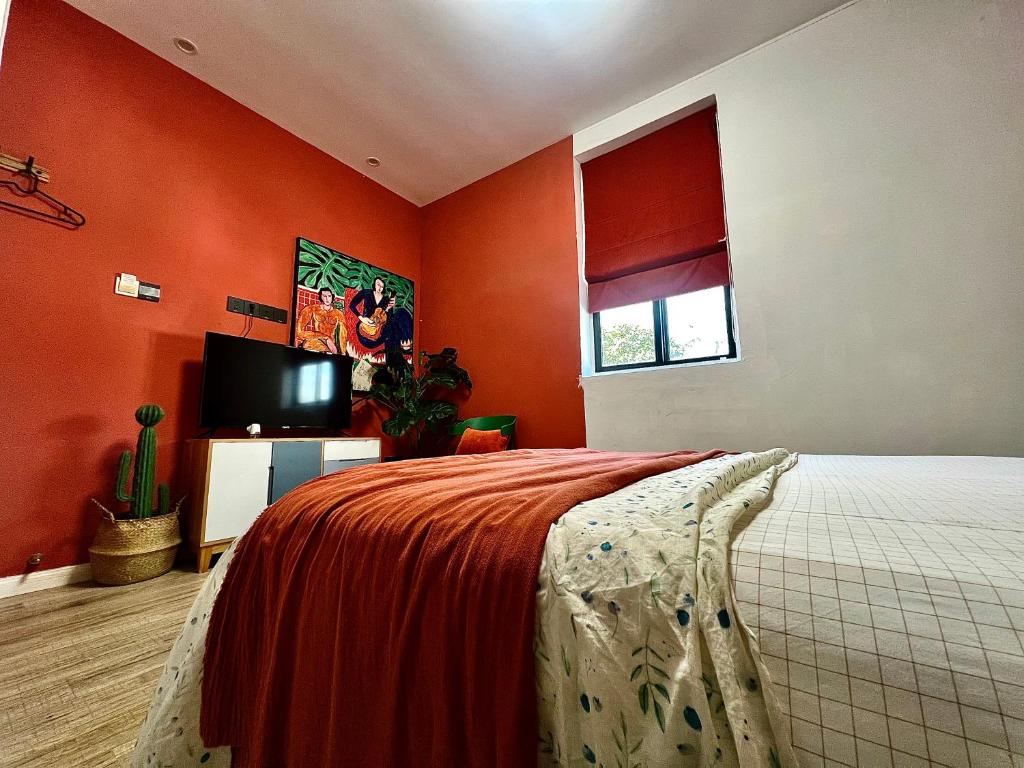 a bedroom with orange walls and a bed and a tv at Shanghai Guiwu Village Near Disney Resort in Shanghai