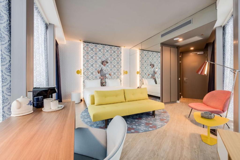 een hotelkamer met een gele bank en een slaapkamer bij nhow Amsterdam Rai in Amsterdam