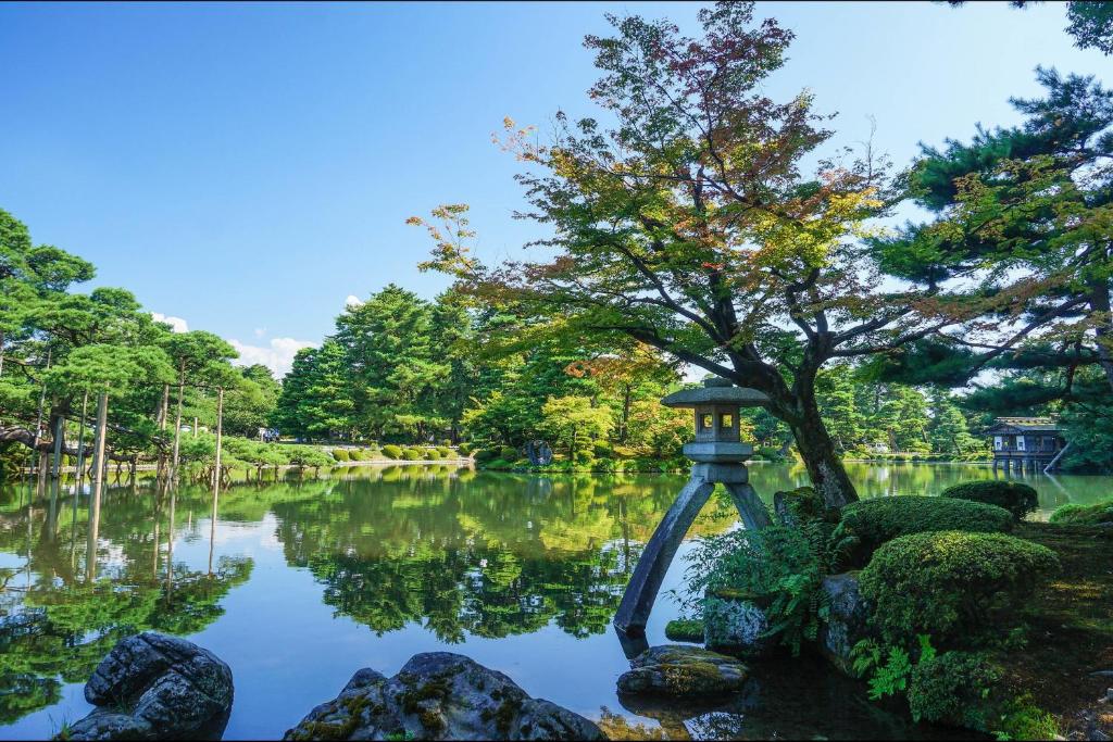 a japanese garden with a tree and a pond at HOTEL MYSTAYS PREMIER Kanazawa in Kanazawa