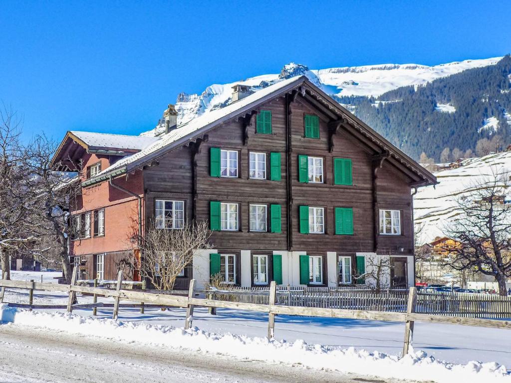 una grande casa in legno con persiane verdi nella neve di Apartment Chalet Chilchboden by Interhome a Grindelwald