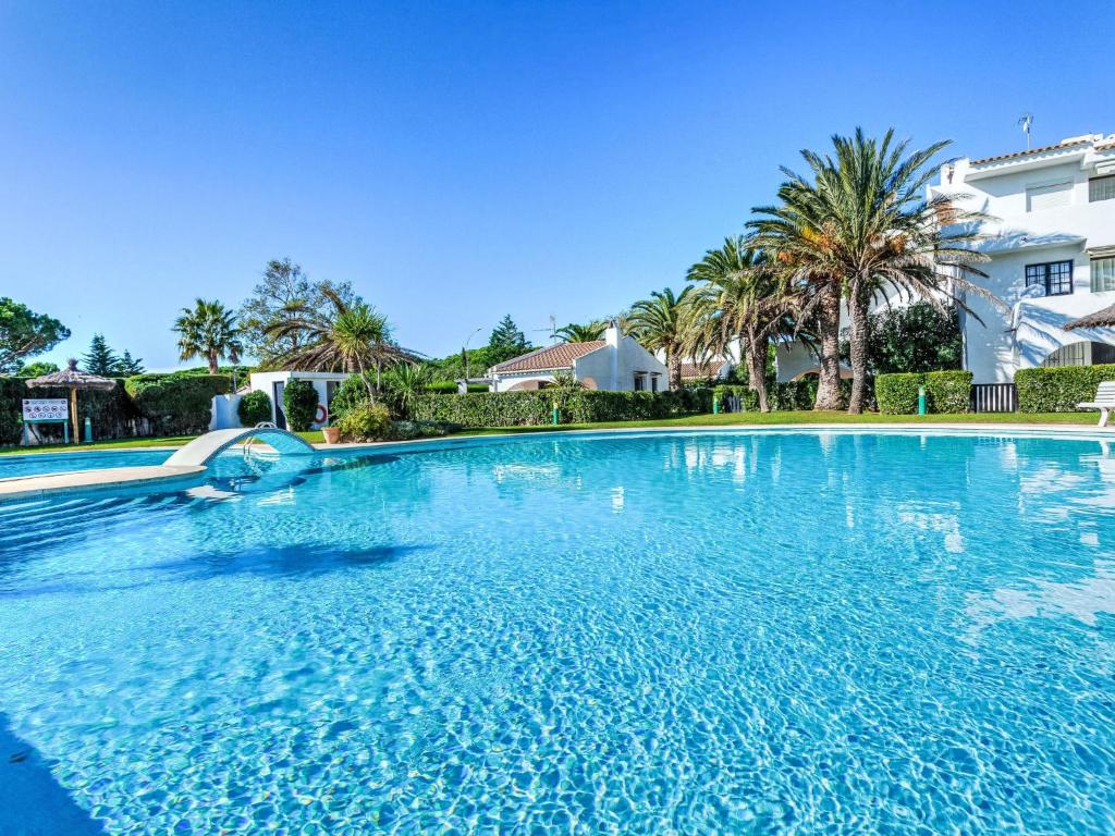 a large swimming pool in a yard with palm trees at Apartment Ducado Golf B II by Interhome in Pals