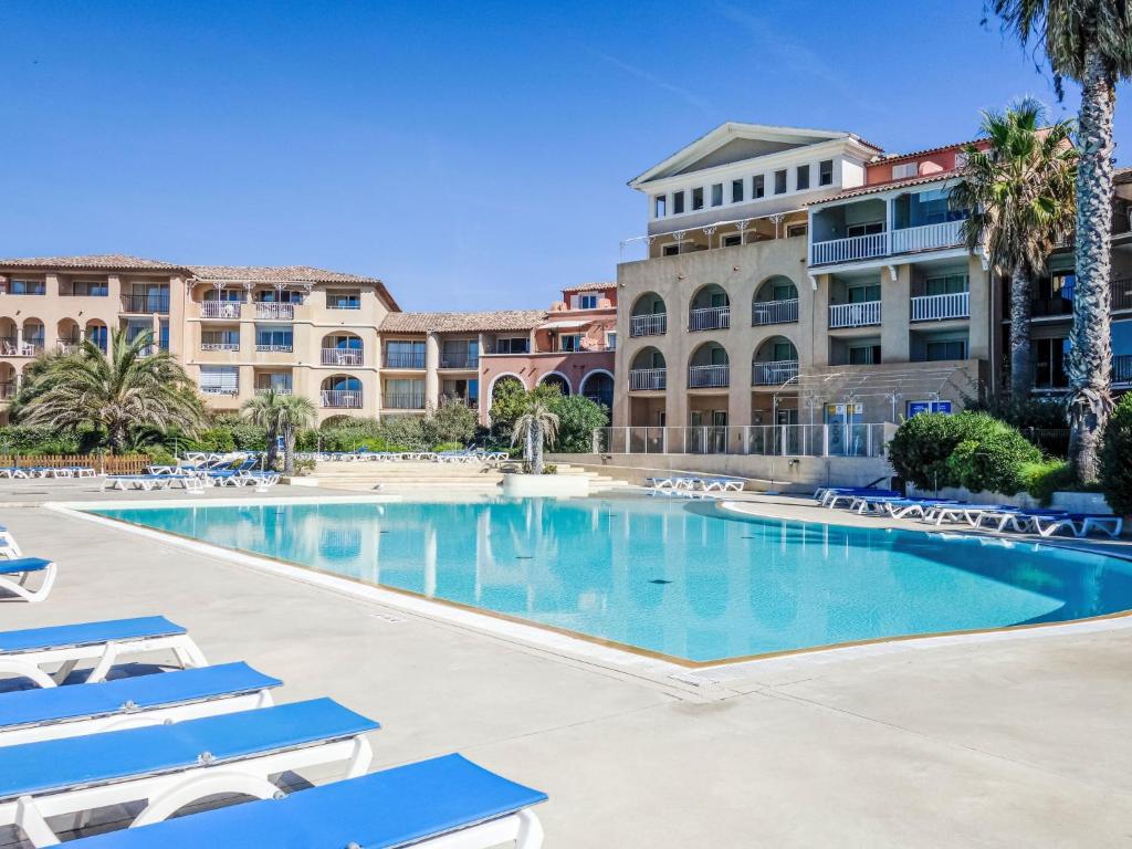 une piscine avec des chaises longues devant un immeuble dans l'établissement Apartment Les Rivages de Coudoulière-32 by Interhome, à Six-Fours-les-Plages