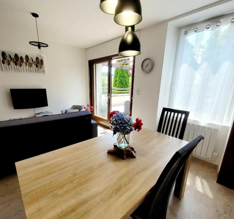 ein Esstisch mit einer Vase mit Blumen darauf in der Unterkunft Vacances en famille 4 étoiles à 30min des pistes de Ski Mont Dore Sancy in Messeix