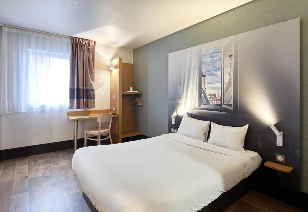 a hotel room with a large bed and a desk at B&B HOTEL Paris Le Bourget in Le Bourget