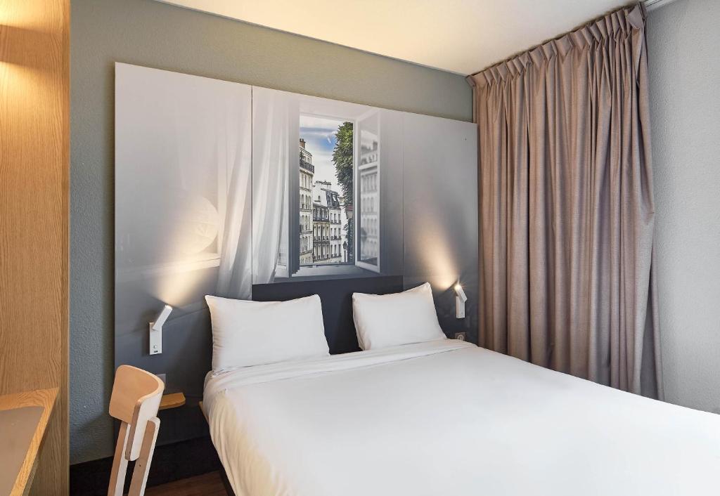 a bedroom with a large bed and a window at B&B HOTEL Paris Le Bourget in Le Bourget