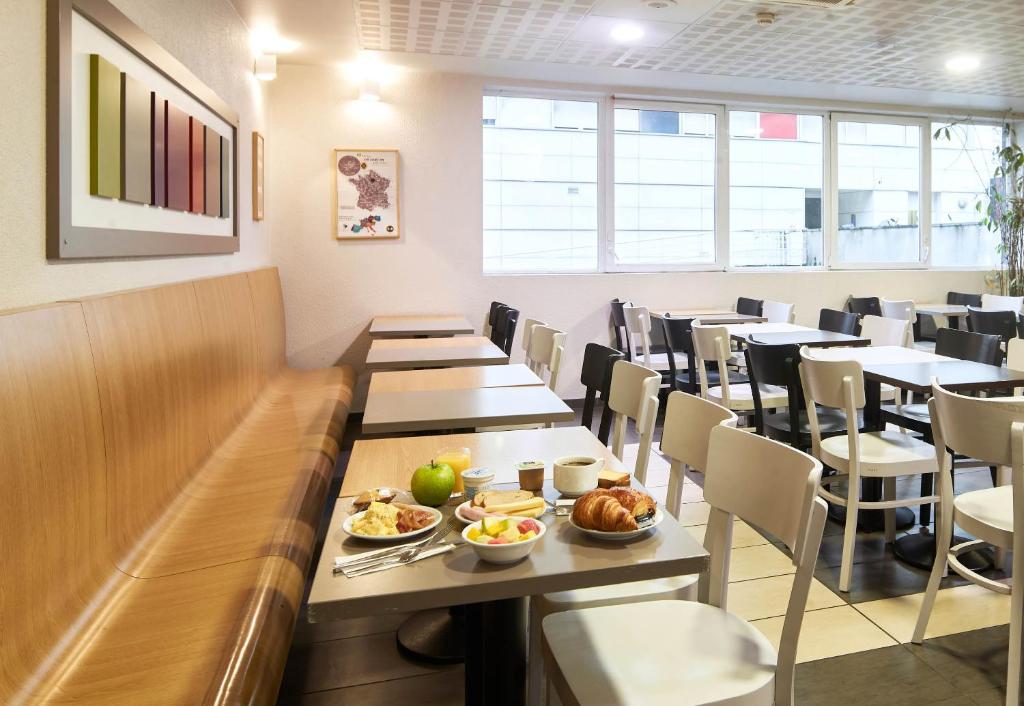 a dining room with tables and chairs with food on them at B&B HOTEL Paris Le Bourget in Le Bourget