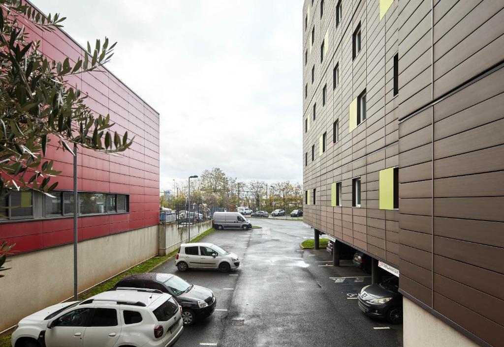 a parking lot with cars parked next to a building at B&B HOTEL Paris Le Bourget in Le Bourget