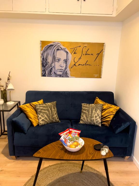 - un canapé bleu avec un bol de fruits sur une table basse dans l'établissement Studio Paris Central, à Paris