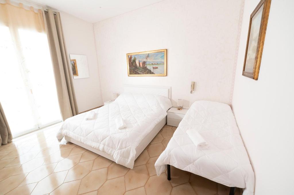 a white bedroom with a bed and a bench at Domus61 in Marsala