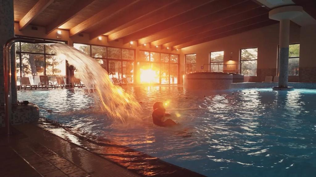 a person in a swimming pool with a fountain at Olive Family Suites - Hotel & Resort Adria Ankaran in Ankaran