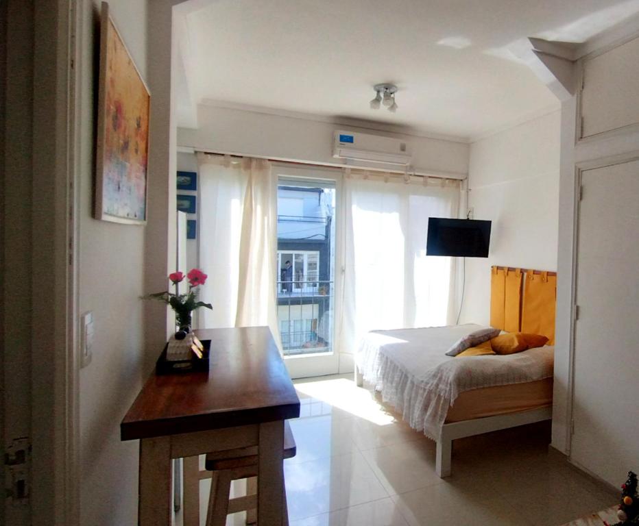 a bedroom with a bed and a table and a window at monoambiente Gascón in Mar del Plata