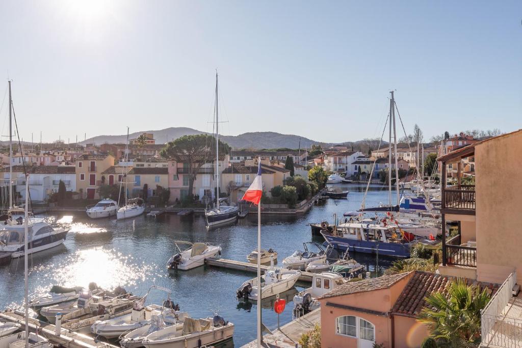un groupe de bateaux amarrés dans un port de plaisance comportant des bâtiments dans l'établissement L'Ammarage YourHostHelper, à Grimaud