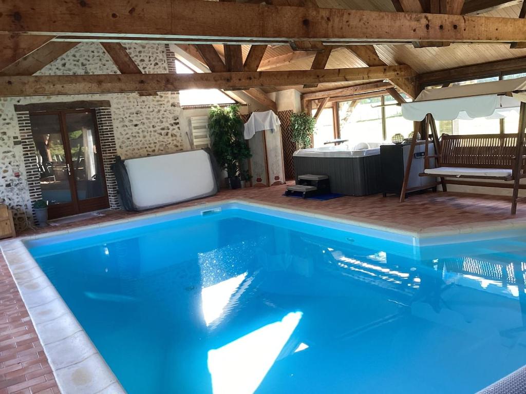 une grande piscine bleue dans une maison dans l'établissement La Fontaine du Perche - Piscine Spa Sauna Home cinema, à La Livarderie
