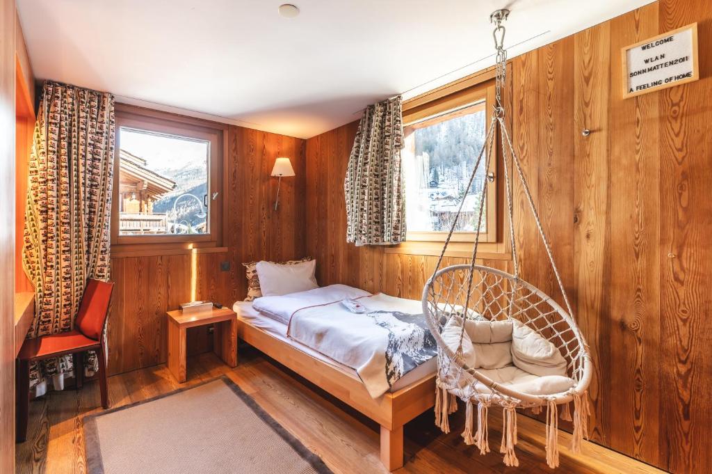 ツェルマットにあるSonnmatten Boutique Hotel & Apartments Zermattのベッドルーム1室(スイングベッド1台、椅子付)