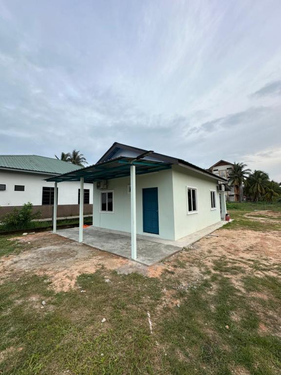 a small white house with a blue roof at Teratak Manis Homestay in Kuantan