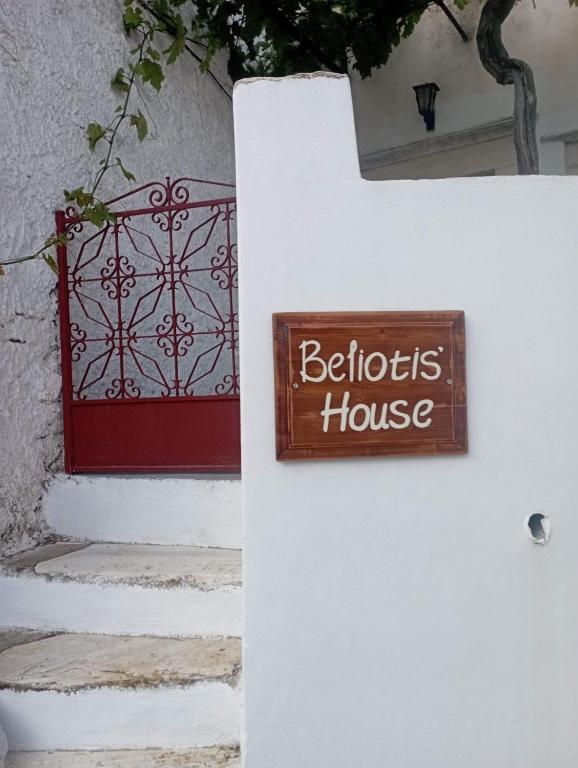 a sign on the side of a house with a red door at Beliotis' House in Apérathos