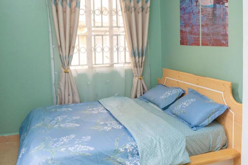 カンパラにあるesteez houseの青いシーツのベッドと窓のある寝室