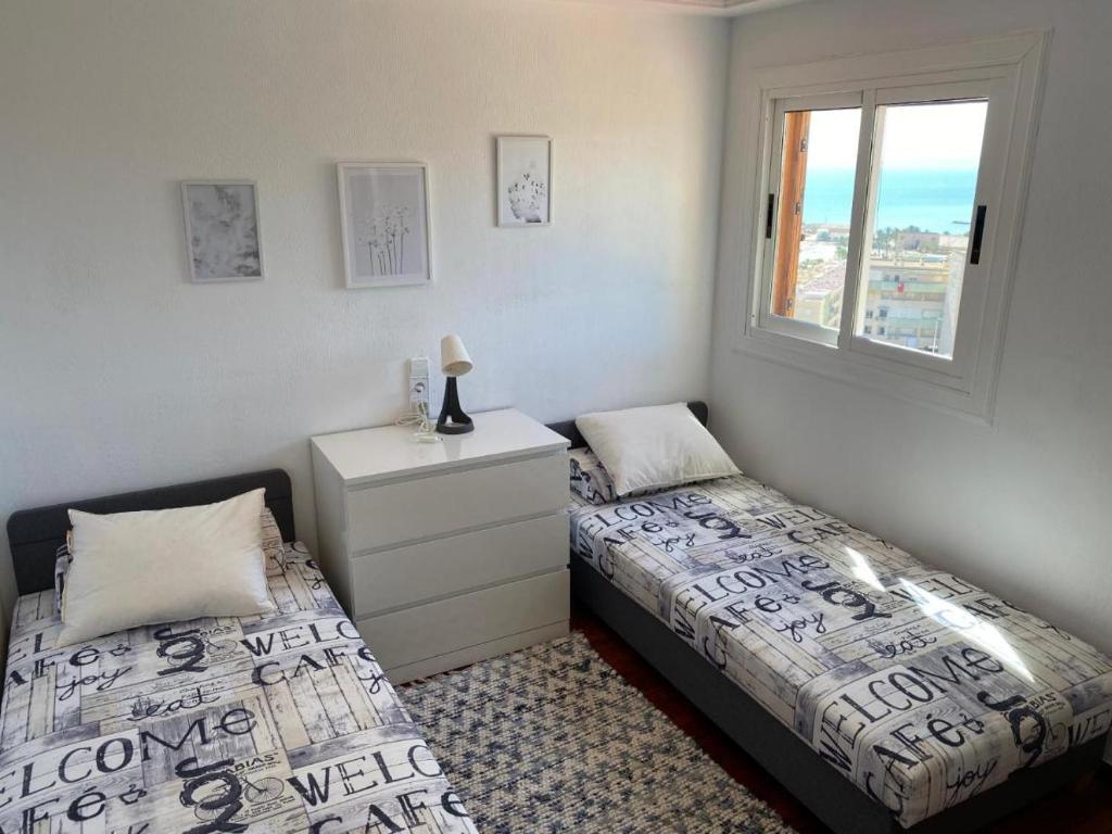 a bedroom with two beds and a dresser and a window at Appartement 3 chambres, piscine et vue mer in Santa Pola