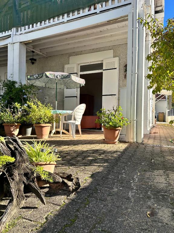 un patio avec une table, des chaises et un parasol dans l'établissement 2 chambres Arcachon & Moulleau accès Plage - Salle de bain & coin petit déjeuner, à Arcachon