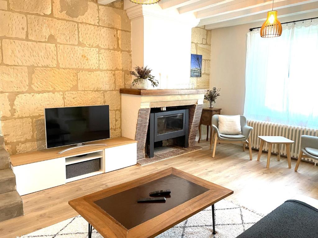 un salon avec une cheminée et une télévision dans l'établissement Ailanthus, à Saint-Aignan