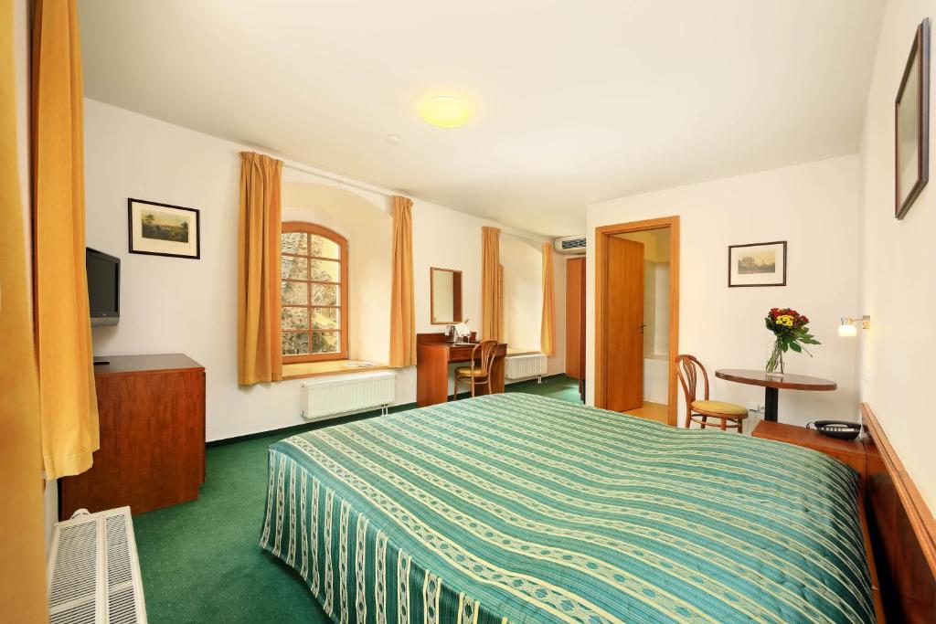 a hotel room with a bed and a table at Hotel Mlýn in Český Krumlov