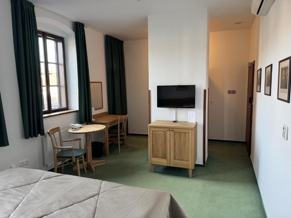 a room with a bed and a tv and a table at Hotel Mlýn in Český Krumlov