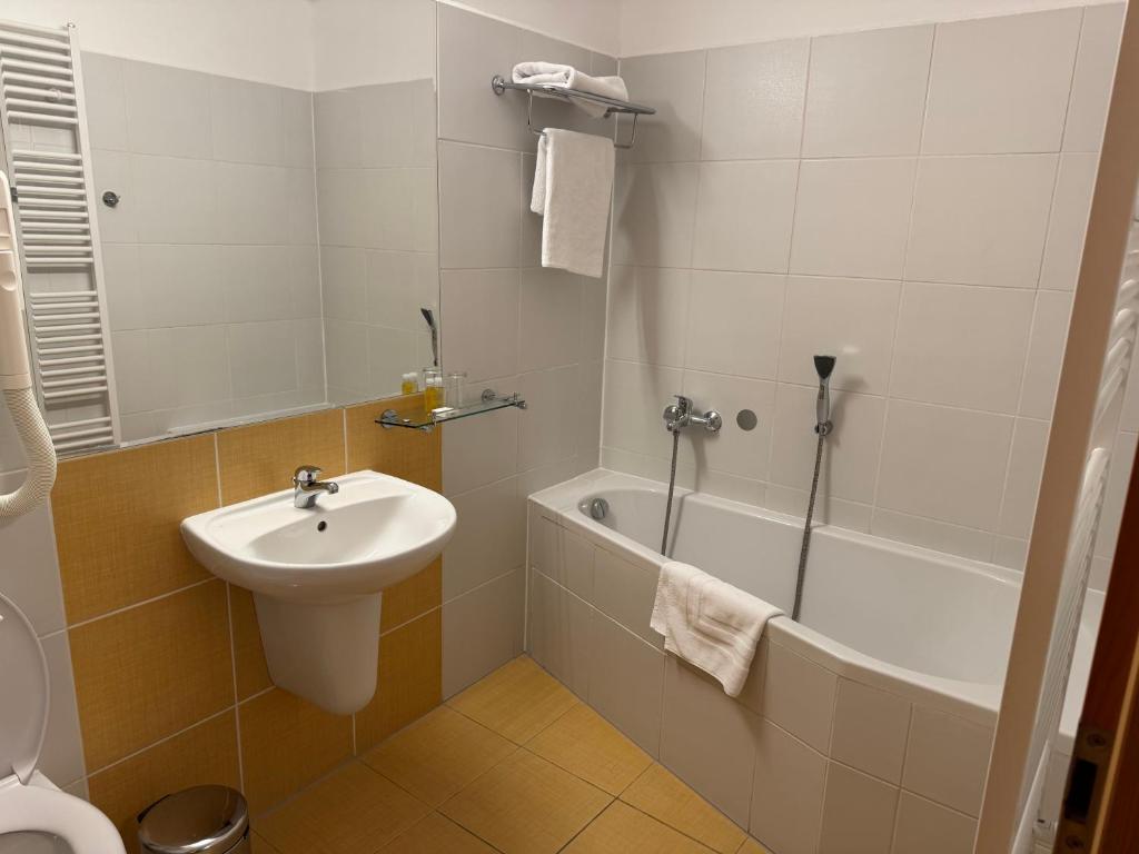 a bathroom with a sink and a tub and a toilet at Hotel Mlýn in Český Krumlov