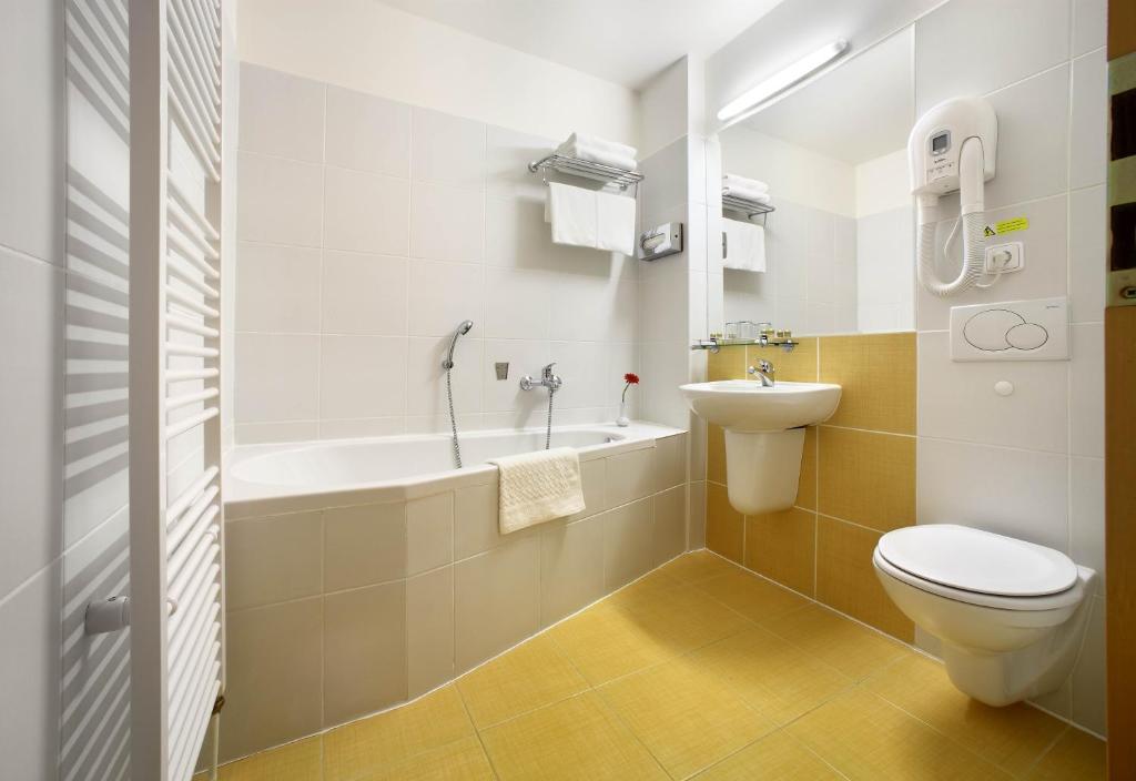 a bathroom with a toilet and a tub and a sink at Hotel Mlýn in Český Krumlov